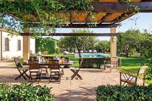 A covered outdoor dining area with a pool in the background. - Villa Krizia - Private villa near Syracuse (Isola)