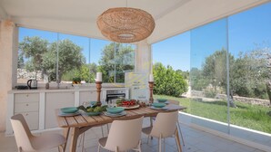 A modern kitchen with large windows, a dining table set for four, and a view of the surrounding landscape. - TD Trulli Benedetta w/ Pool in Peaceful Nature (Castellana Grotte)