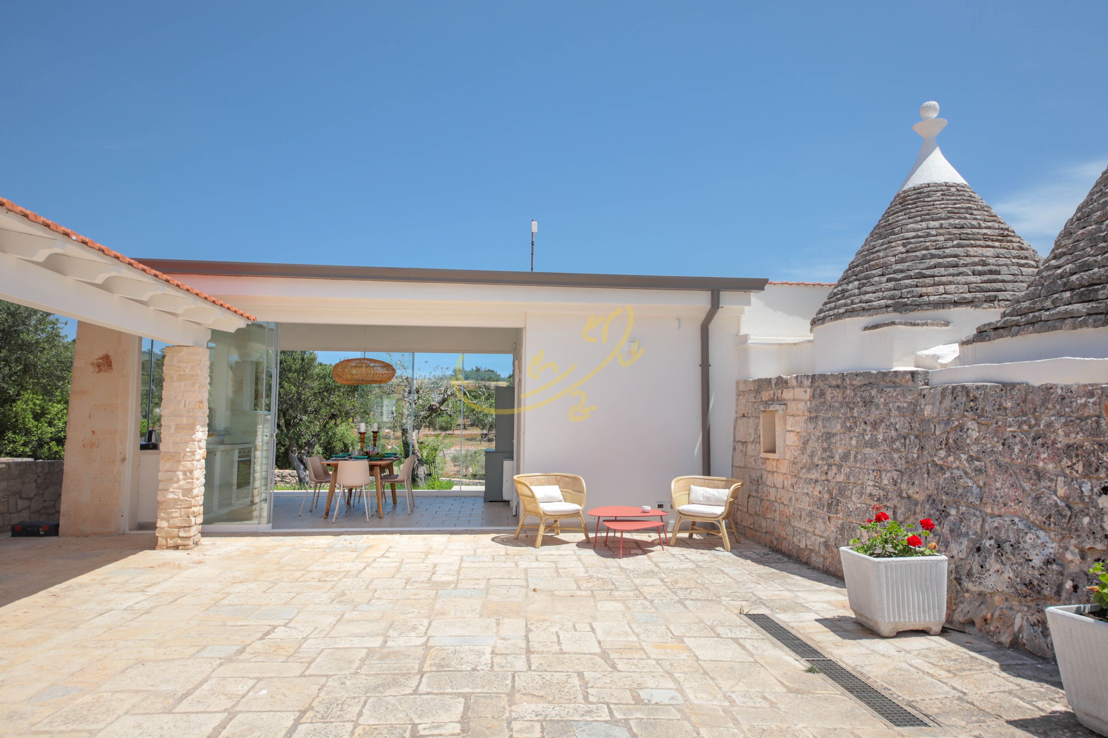 A patio area with stone flooring, wicker furniture, and potted plants.