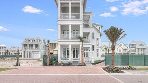 A multi-story residential building with a central entrance, balconies, and a gated driveway.