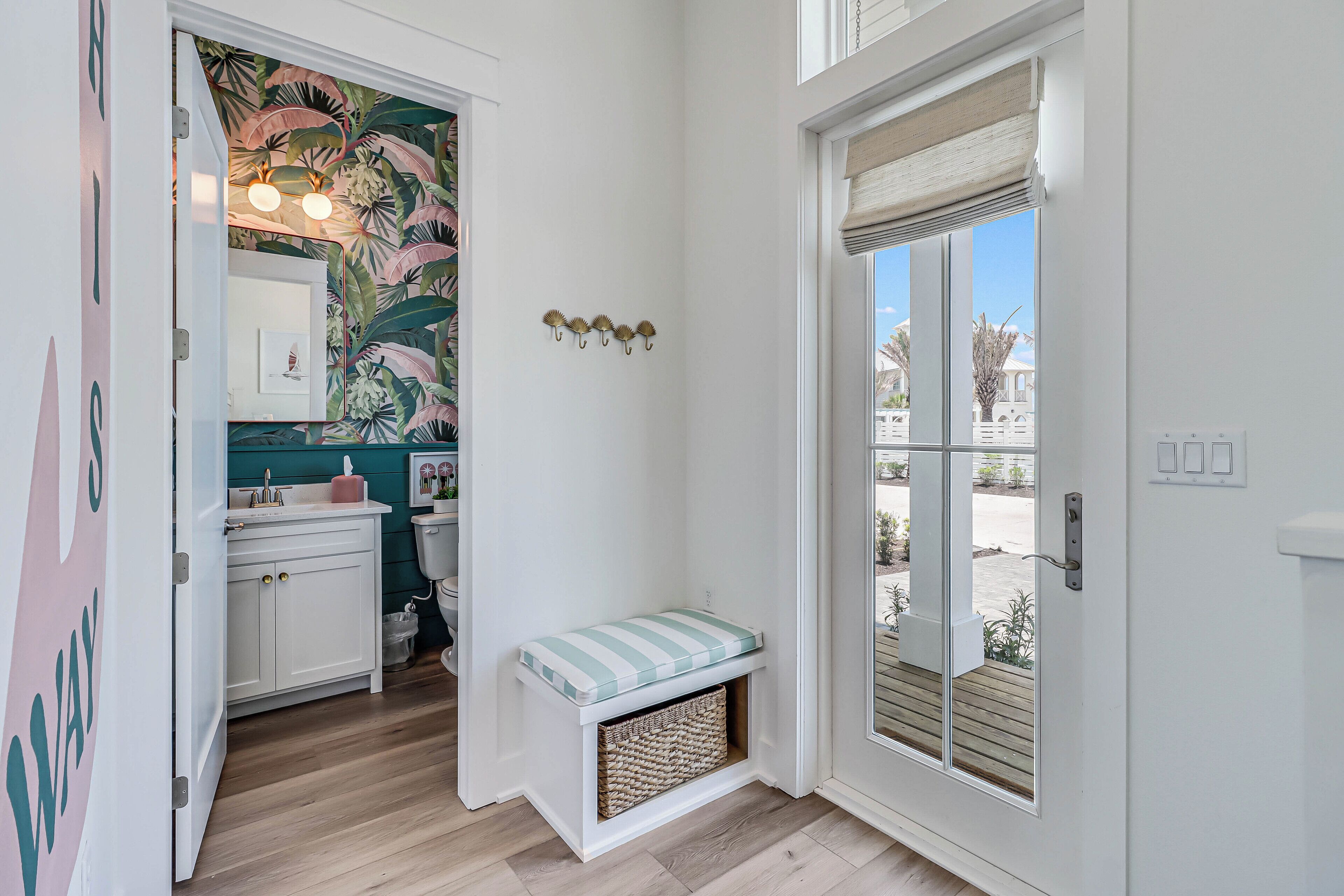 A bathroom with a toilet, sink, and a bench with a basket underneath.