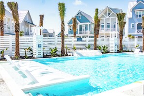 Relax by the serene pool surrounded by palm trees and nautical-themed buildings.