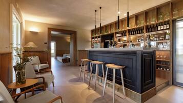 Un área de bar con taburetes, estantes llenos de botellas y una barra.