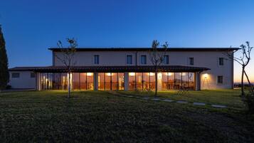 Ein modernes, zweistöckiges Haus mit überdachter Terrasse, großen Fenstern und einem gepflegten Rasen.
