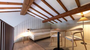 A modern loft bedroom with exposed wooden beams, a white sofa, a round table, and a floor lamp.