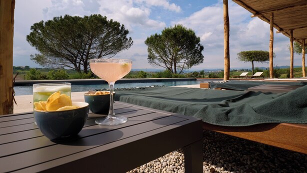 A poolside setting with a table, a drink, and snacks. - Colle Alberti Country House (Cerreto Guidi)