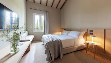 A bedroom with a bed, bedside table, lamp, and a window with curtains.