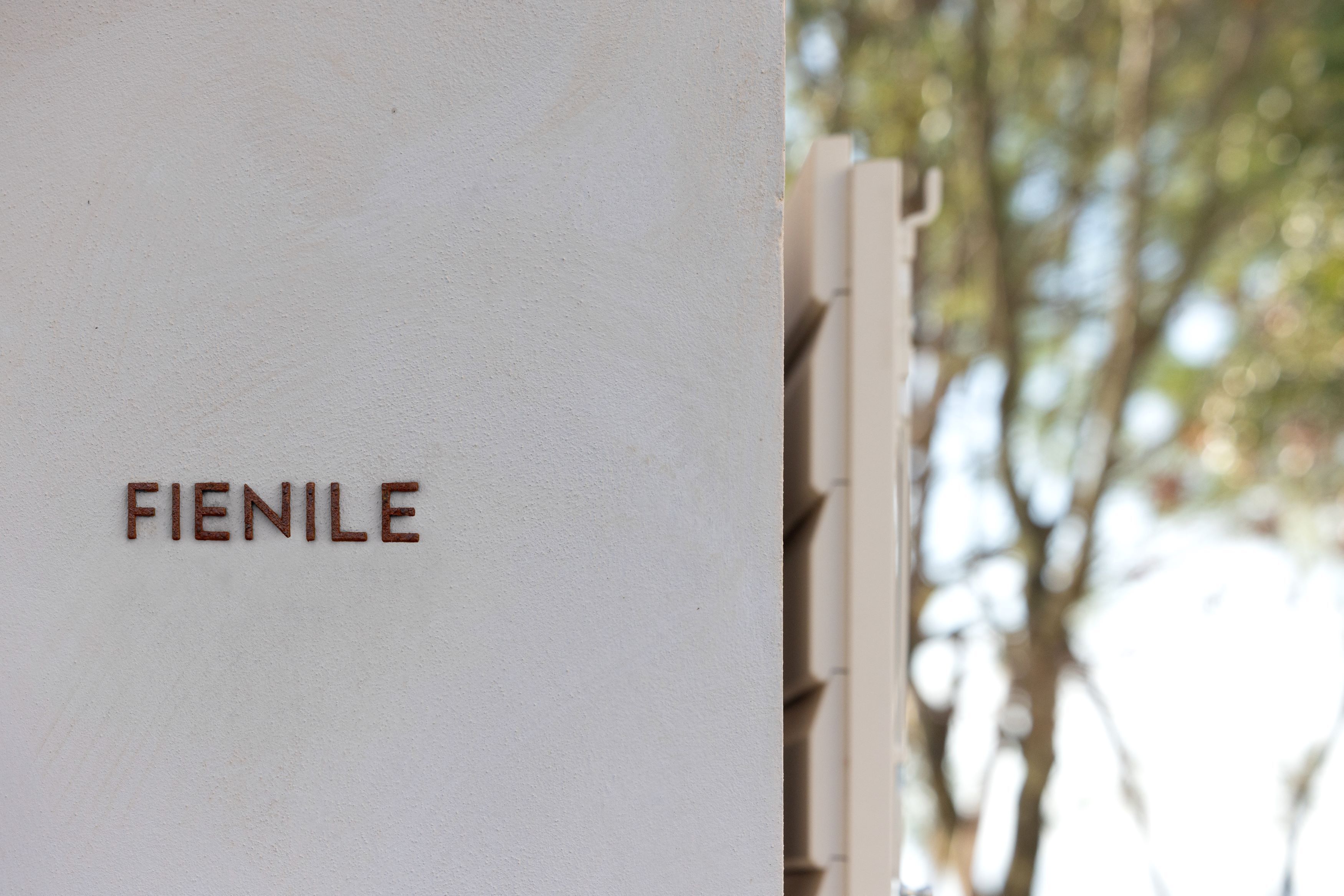 Un mur blanc sur lequel est inscrit le mot « FIENILE » en lettres marron.