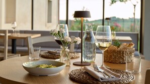 A dining table set with a bowl of food, wine glasses, a vase with flowers, a water bottle, and a basket of bread. - Colle Alberti Country House (Cerreto Guidi)