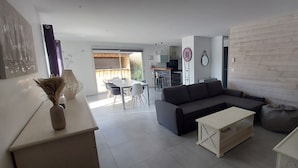 Un saló modern amb un sofà, taula de centre i zona de menjador amb caires i taula.