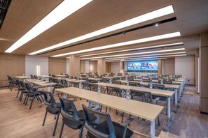 A conference room with multiple tables and chairs, a large screen, and overhead lighting. - Orange Hotel (Beijing Wangjing Subway Station) (Beijing)