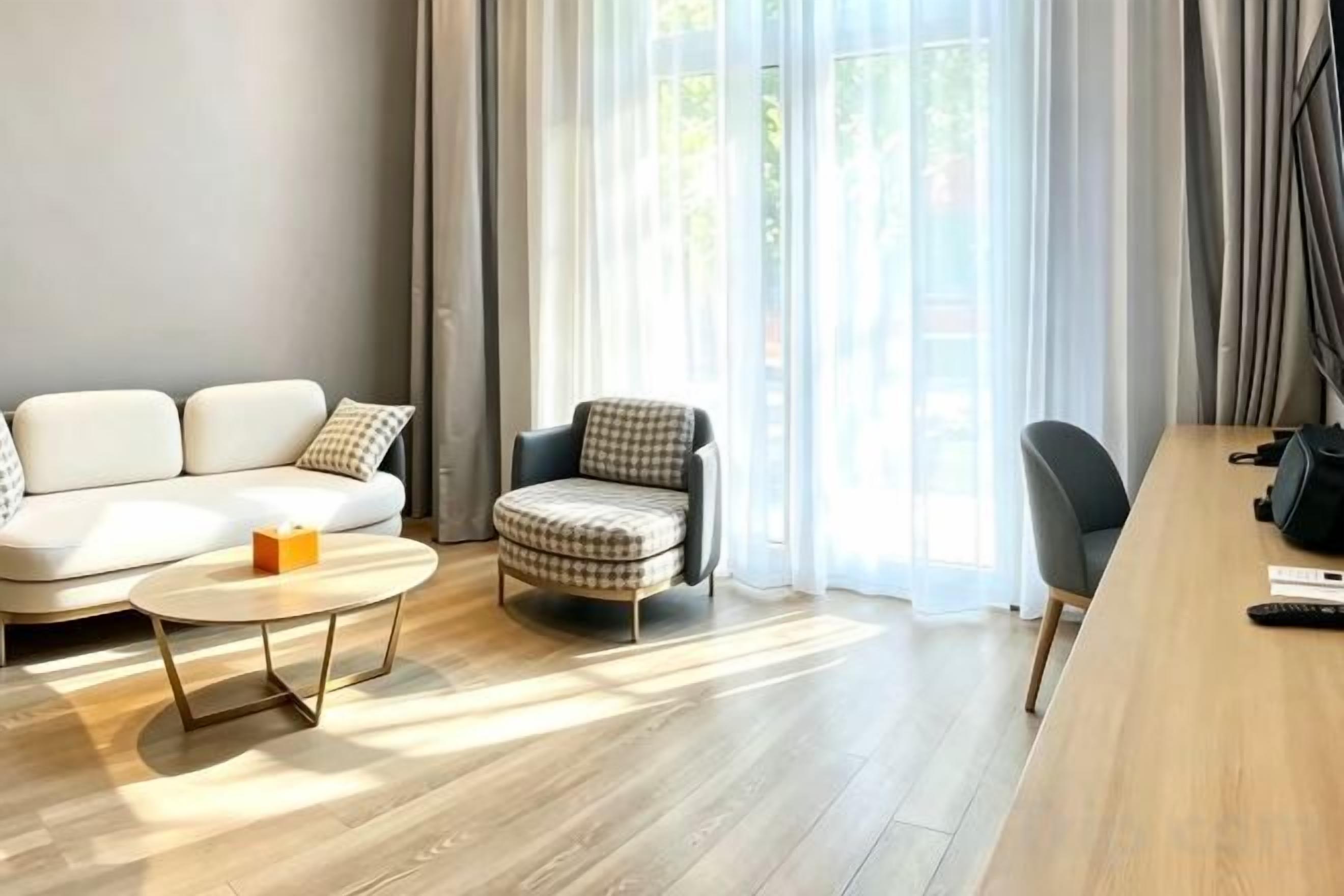A modern living room with a sofa, armchair, coffee table, and a wooden dining table.