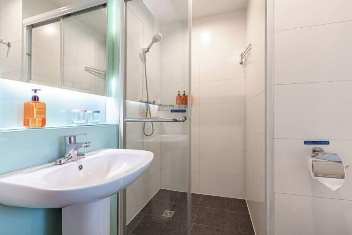 A modern bathroom with a glass shower enclosure, a white sink, and a glass shower door.