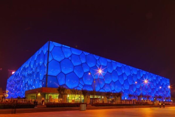 A large, modern building with a distinctive honeycomb-like exterior at night. - Orange Hotel (Beijing Wangjing Subway Station) (Beijing)