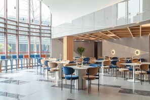 A spacious indoor area with multiple tables and chairs, large windows, and a modern architectural design. - Orange Hotel (Beijing Wangjing Subway Station) (Beijing)