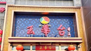 A building with a blue patterned facade and a red sign with Chinese characters. - Orange Hotel (Beijing Wangjing Subway Station) (Beijing)