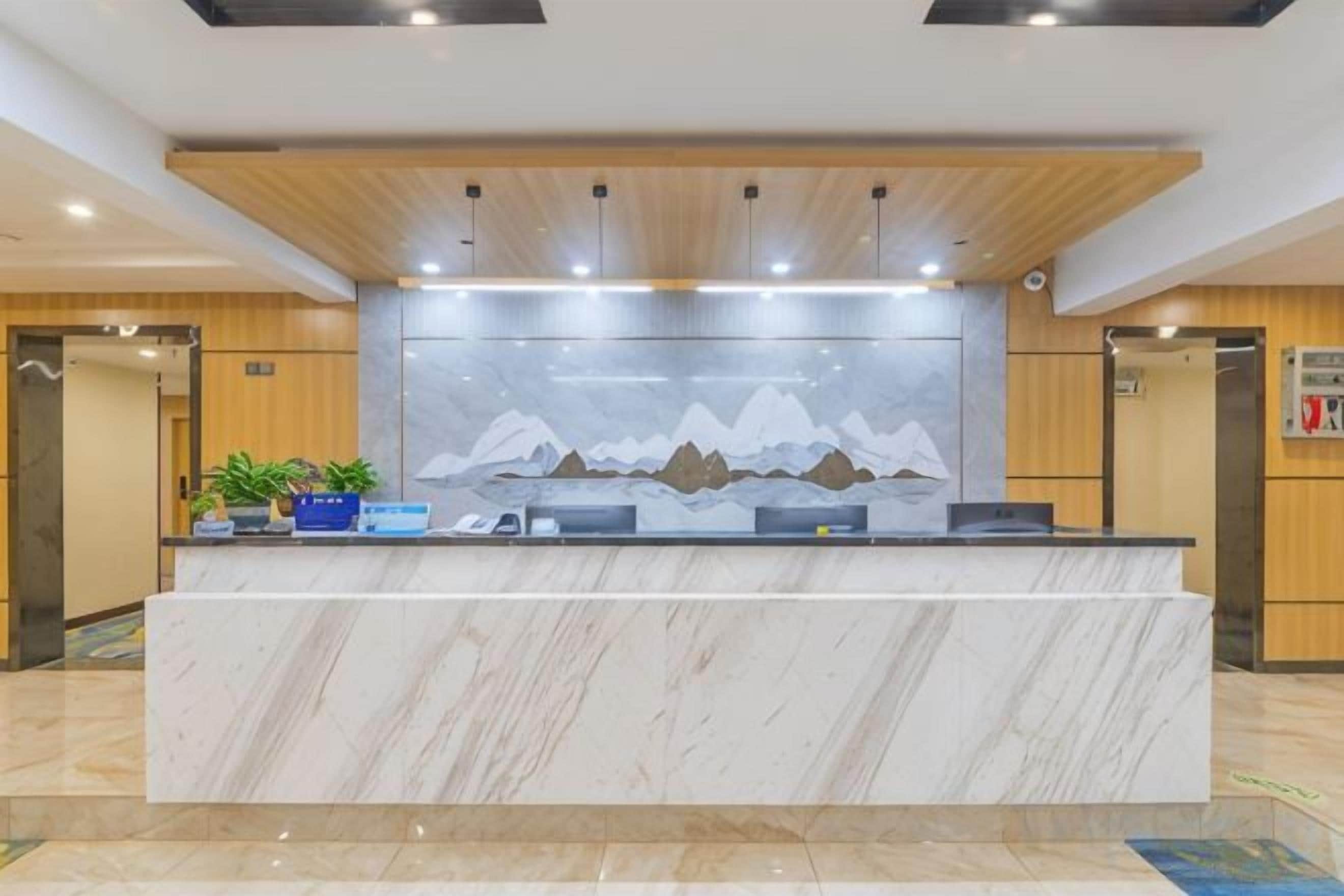 A reception desk with a marble top, a wall-mounted painting of mountains, and a wooden ceiling.
