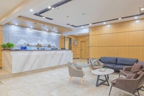A hotel lobby with a reception desk, seating area, and a wall with a mountain design. - Xinyue Business Hotel (Yan'an)