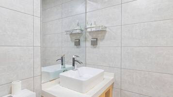 A modern bathroom with a white sink, two faucets, a mirror, and a towel rack.