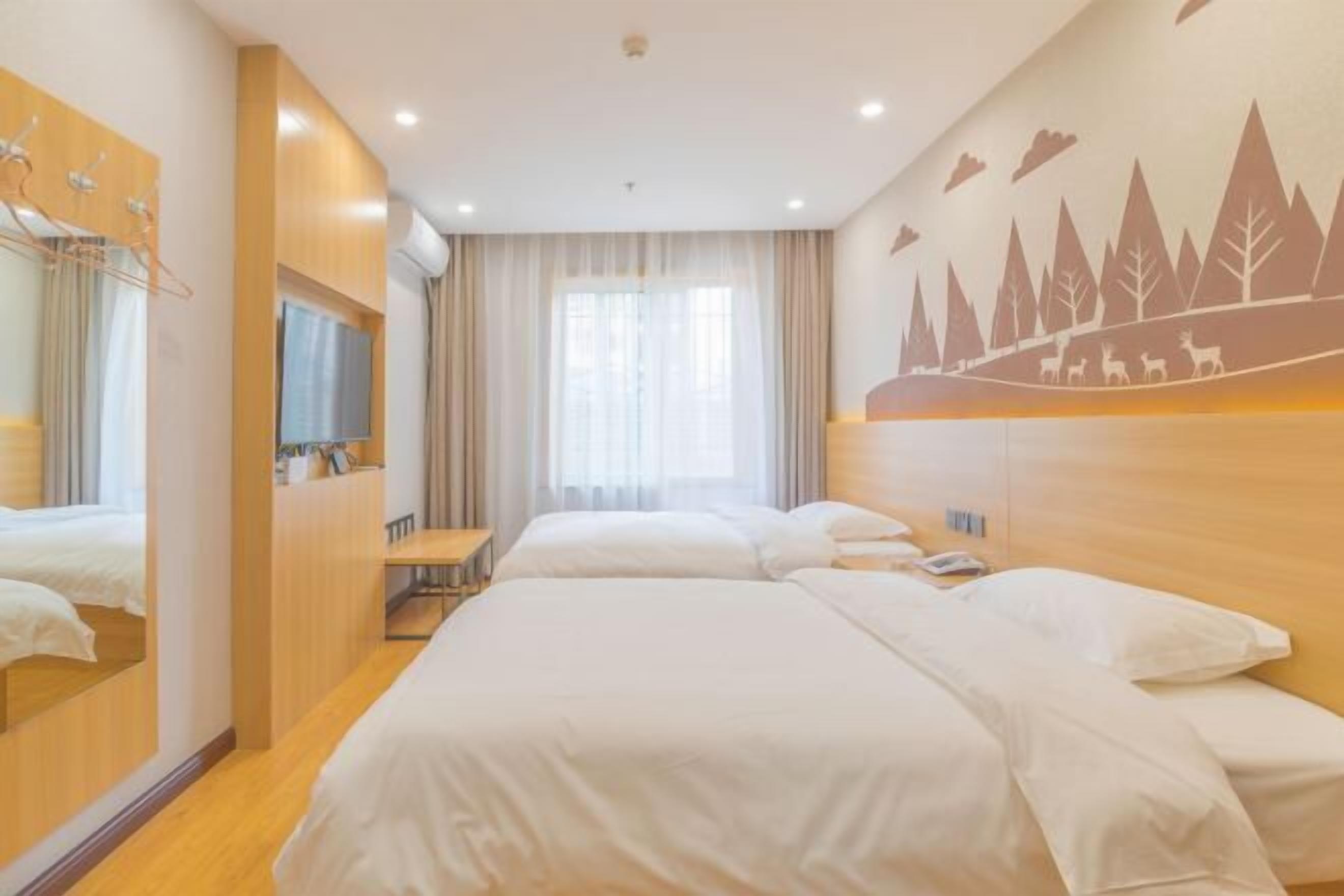 Habitación de hotel con dos camas, un escritorio, un espejo y un mural en la pared.
