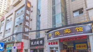 A multi-story building with commercial establishments on the ground floor, including a restaurant and a shop with illuminated signage. - Xinyue Business Hotel (Yan'an)
