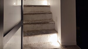 Una scala con finitura in legno e un lampadario in cima.