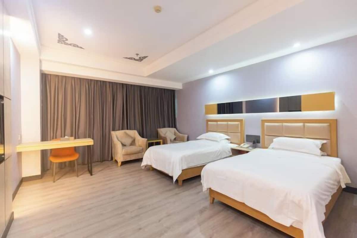 Quarto de hotel com duas camas, uma mesa e uma cadeira.