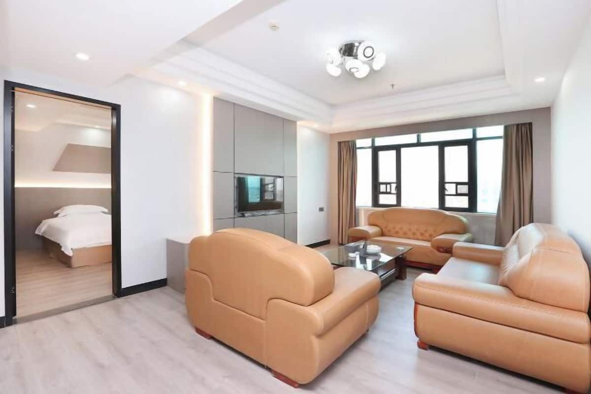 Uma sala de estar moderna com um conjunto de sofá, uma televisão e uma janela grande com cortinas.