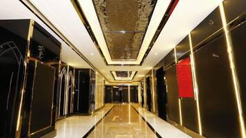A hallway with a reflective floor, a patterned ceiling, and a red accent wall.
