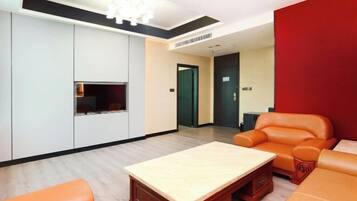 A modern living room with a wooden coffee table, orange leather sofa, and a TV mounted on the wall.