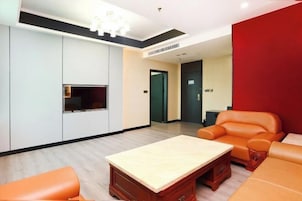 Una sala de estar moderna con una mesa de centro de madera, un sofá de cuero color naranja y un televisor montado en la pared.