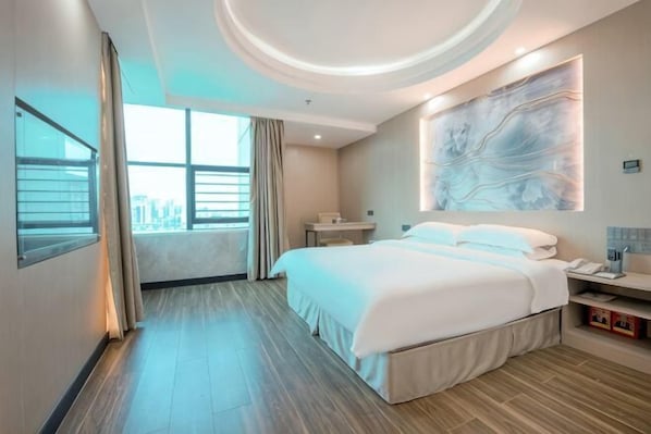 A modern hotel room with a large bed, a desk, a chair, a window with curtains, and a city view.