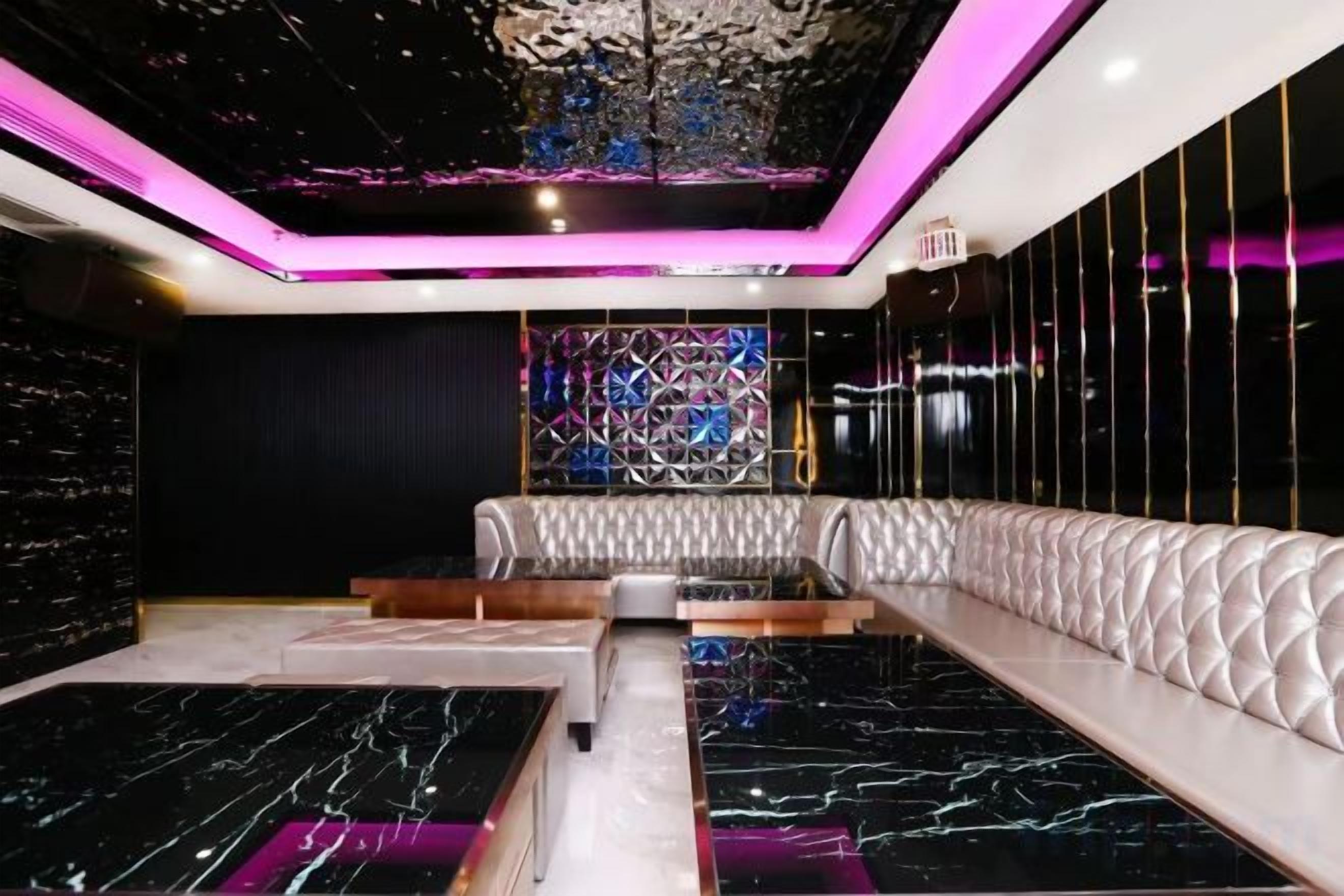 A modern interior with a seating area, a patterned wall, and a ceiling with a unique design.
