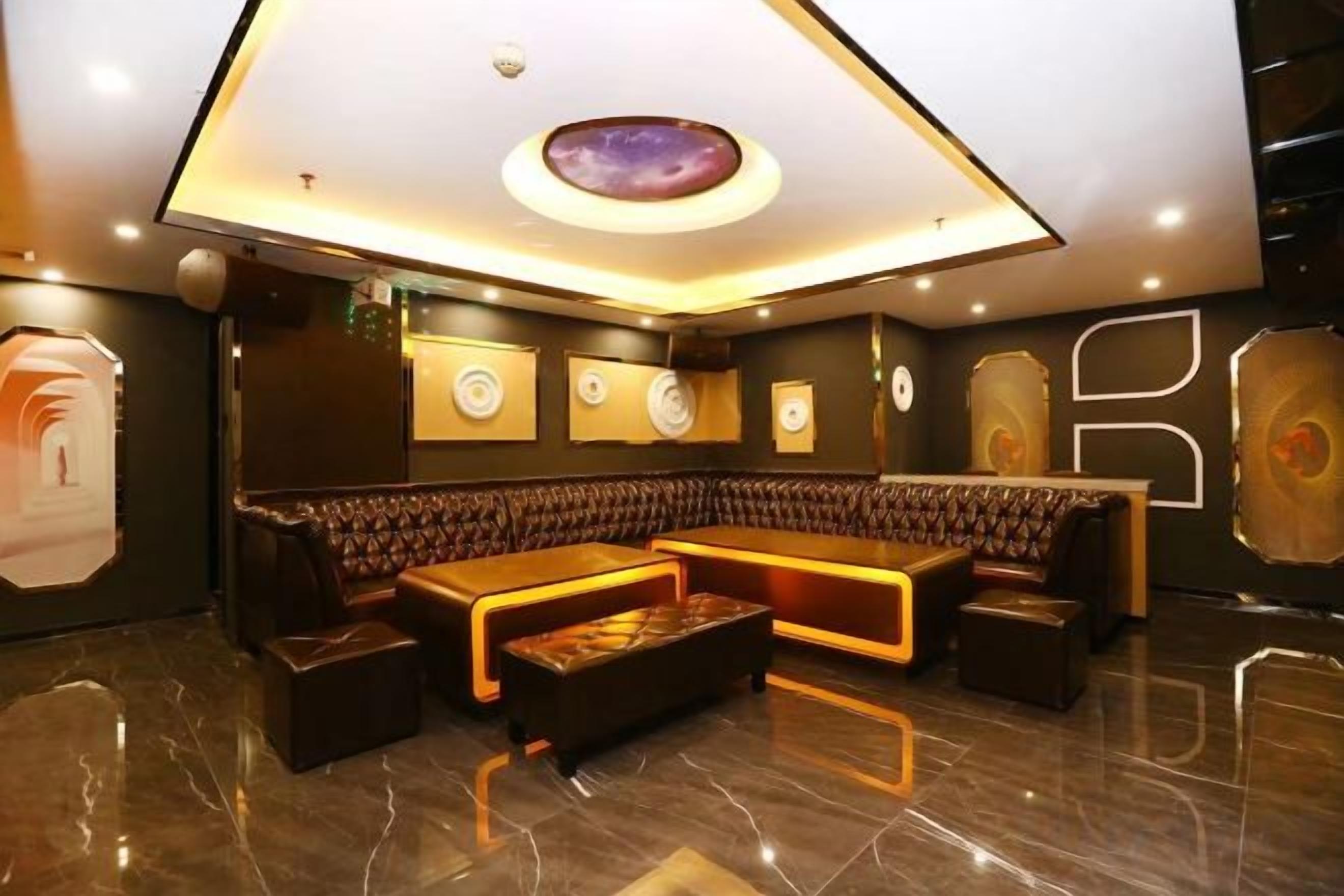 A modern lounge area with a curved seating arrangement, a central coffee table, and a ceiling with a circular light fixture.