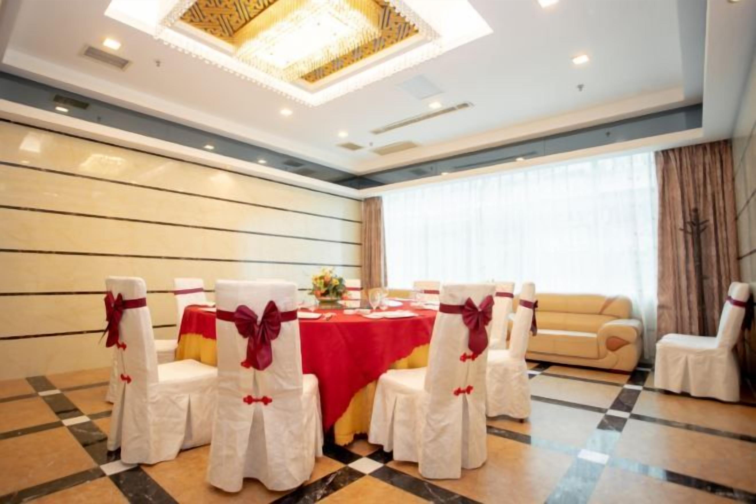 A conference room with a round table, white chairs with red sashes, and a chandelier.