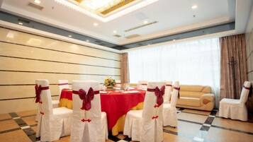 A conference room with a round table, white chairs with red sashes, and a chandelier.