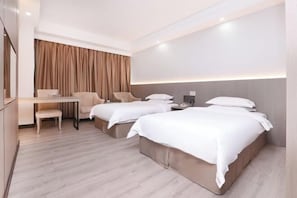 Quarto de hotel com duas camas, uma escrivaninha, uma cadeira e uma janela grande com cortinas.