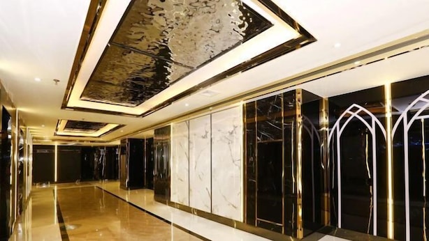 A modern hotel corridor with reflective floors, marble walls, and geometric ceiling designs. - Baohua Hotel (Chaozhou)