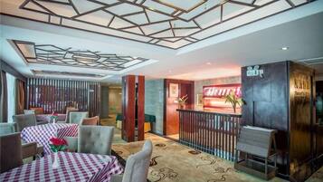 A hotel lobby with checkered tables, a reception desk, and a modern ceiling design.