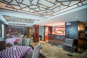 A hotel lobby with checkered tables, a reception desk, and a modern ceiling design.
