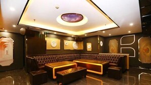 A modern lounge area with a curved sofa, a central ottoman, and a ceiling with a circular skylight. - Baohua Hotel (Chaozhou)