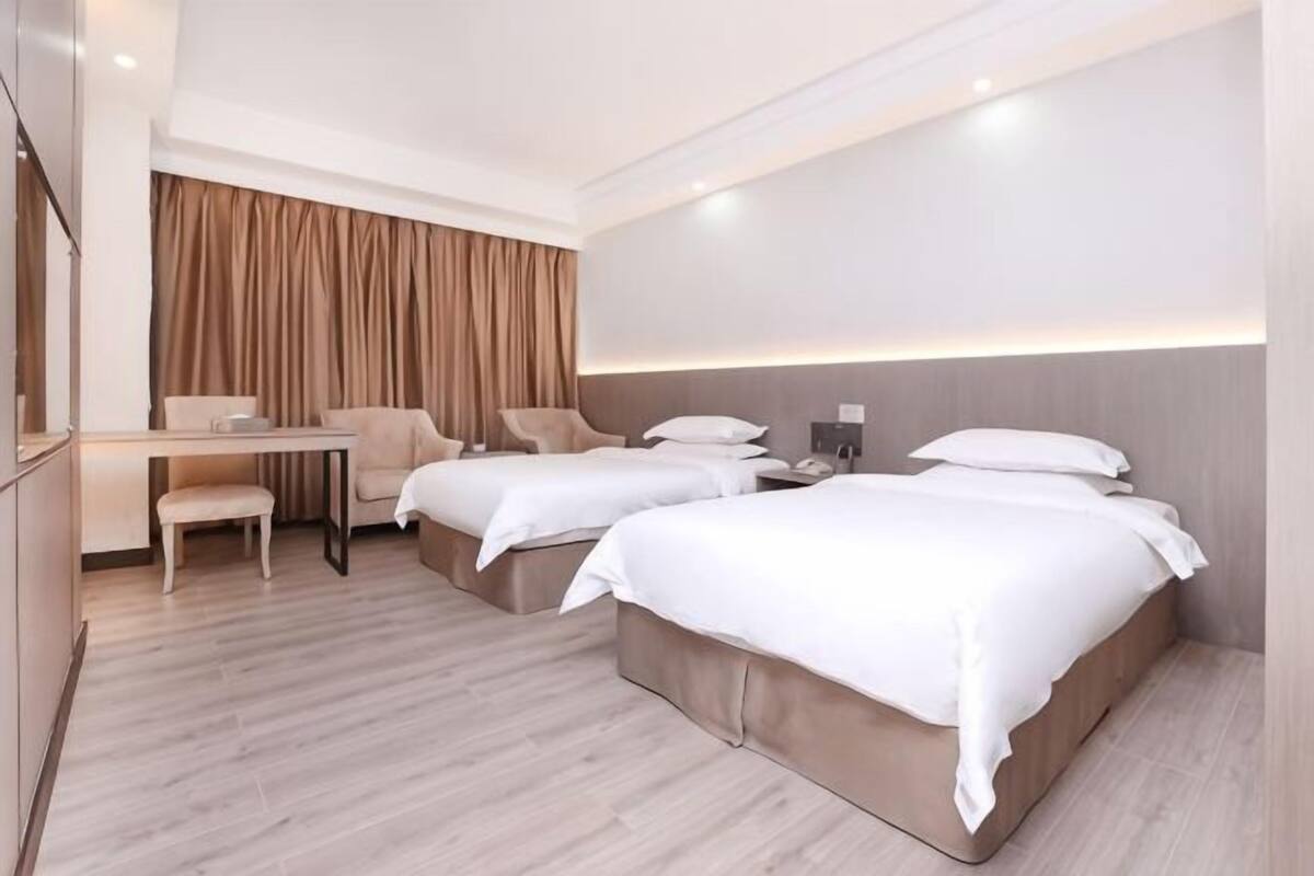 Quarto de hotel com duas camas, uma mesa e uma cadeira.