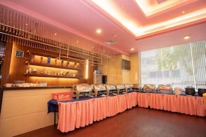 A buffet setup with multiple serving stations and a long table covered with a pink tablecloth. - Baohua Hotel (Chaozhou)