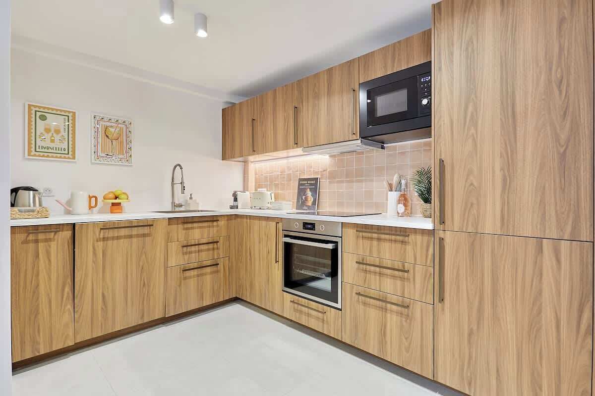 A modern kitchen with wooden cabinets, a built-in oven, and a microwave.