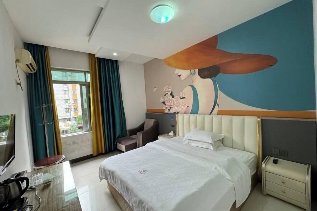 A hotel room with a bed, a desk, a chair, a TV, and a large window with curtains.