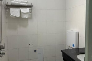 A bathroom with white tiles, a shower, a toilet, and a towel rack with towels. - Fogang Xingshu Fashion Hotel (Fogang)