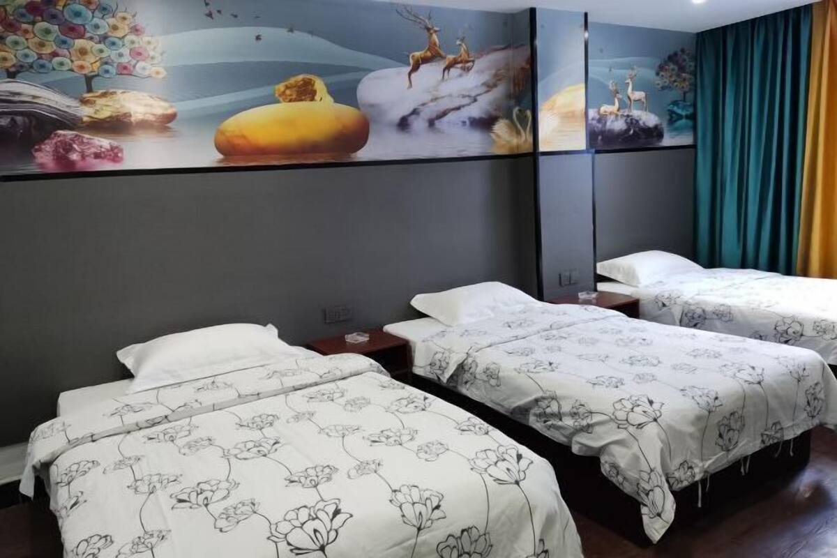 A hotel room with three beds, a large wall mural, and a window with curtains.