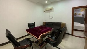 A room with a dining table, chairs, a sofa, an air conditioning unit, and a bed in the corner. - Fogang Xingshu Fashion Hotel (Fogang)