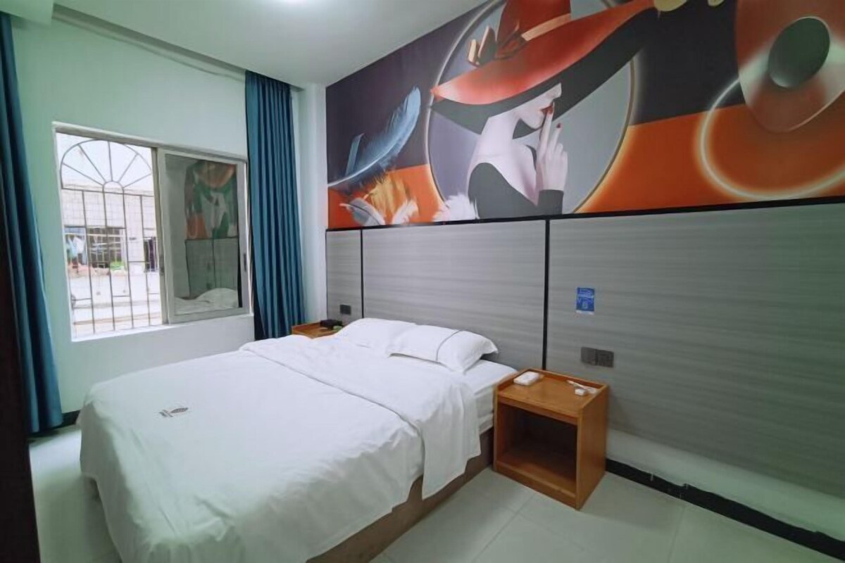 A hotel room with a bed, a nightstand, a window with curtains, and a wall mural.