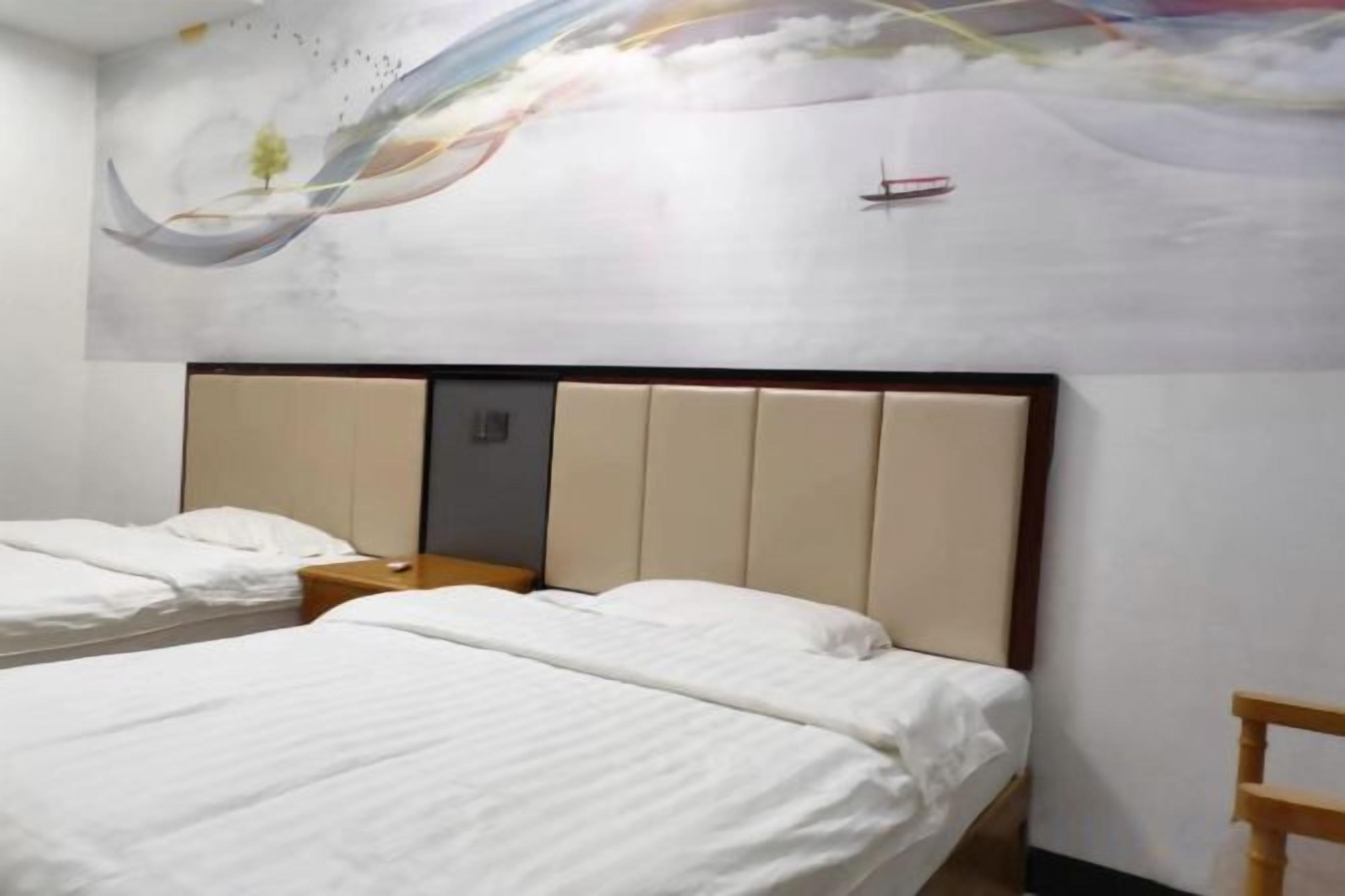 A hotel room with two beds, a headboard, a nightstand, and a wall with a decorative mural.